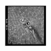 1940s vintage black and white photo print of two women in bathing suits floating on water; one model face up and the other face down, captured from a bird’s-eye view, showcasing serene summer leisure