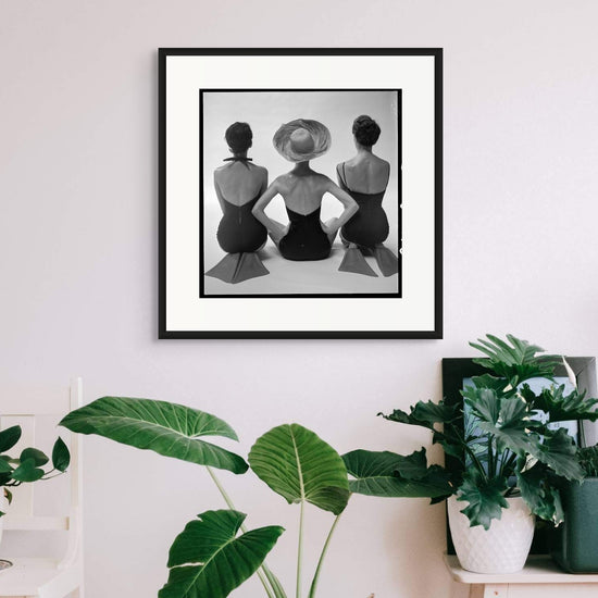 1950s vintage photo of three stylish women in swimsuits and flippers seated in a studio, exuding playful energy and retro elegance, perfect for a nostalgic decor accent.